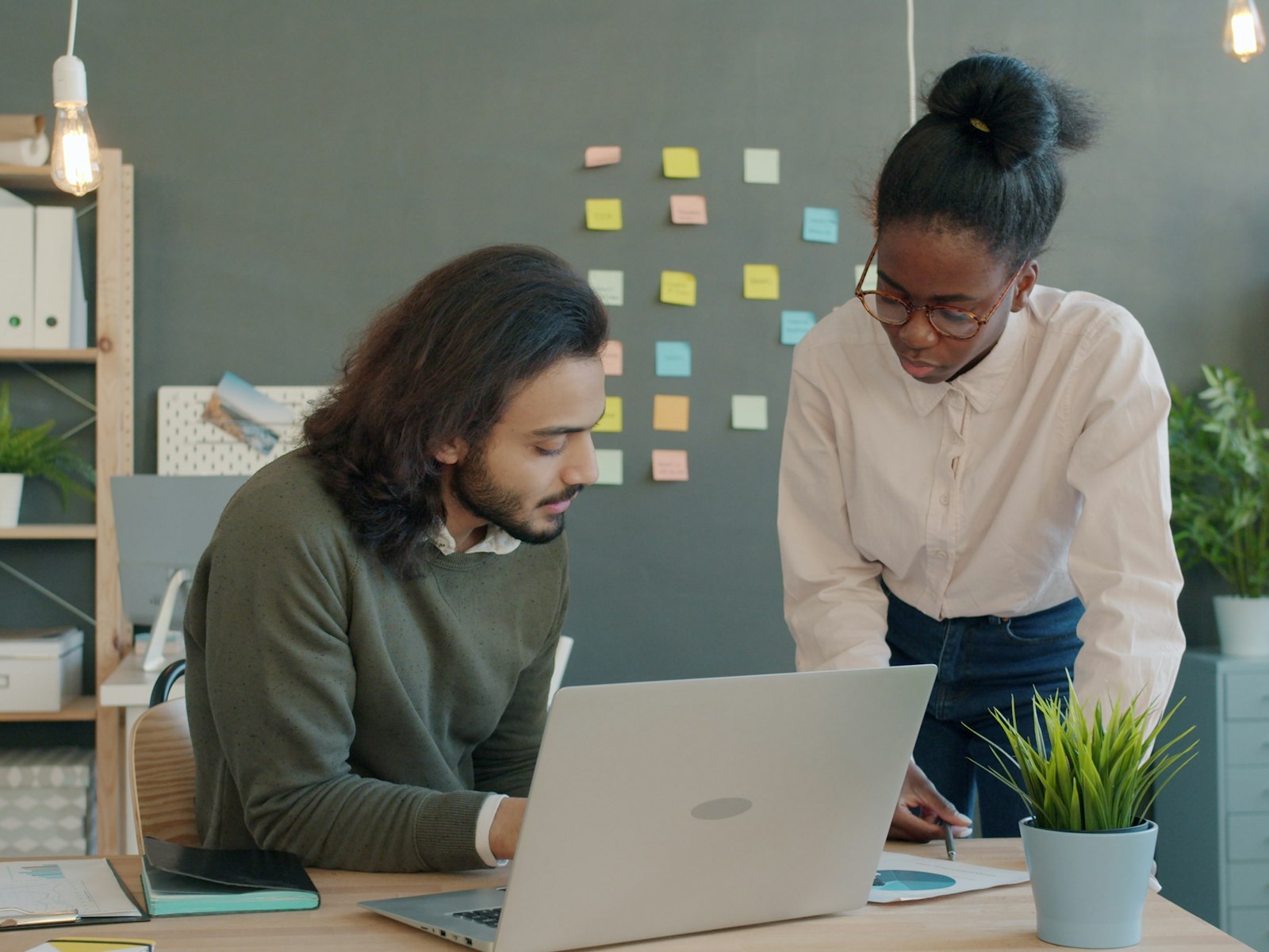 Colleagues reviewing applications and a laptop together at a workplace desk